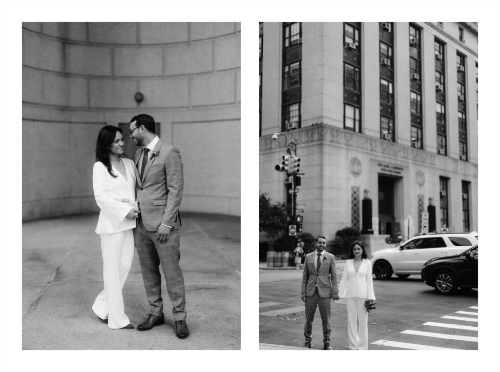 a man wearing a suit and a woman wearing a chic white suit stand outside city hall after eloping in New York city