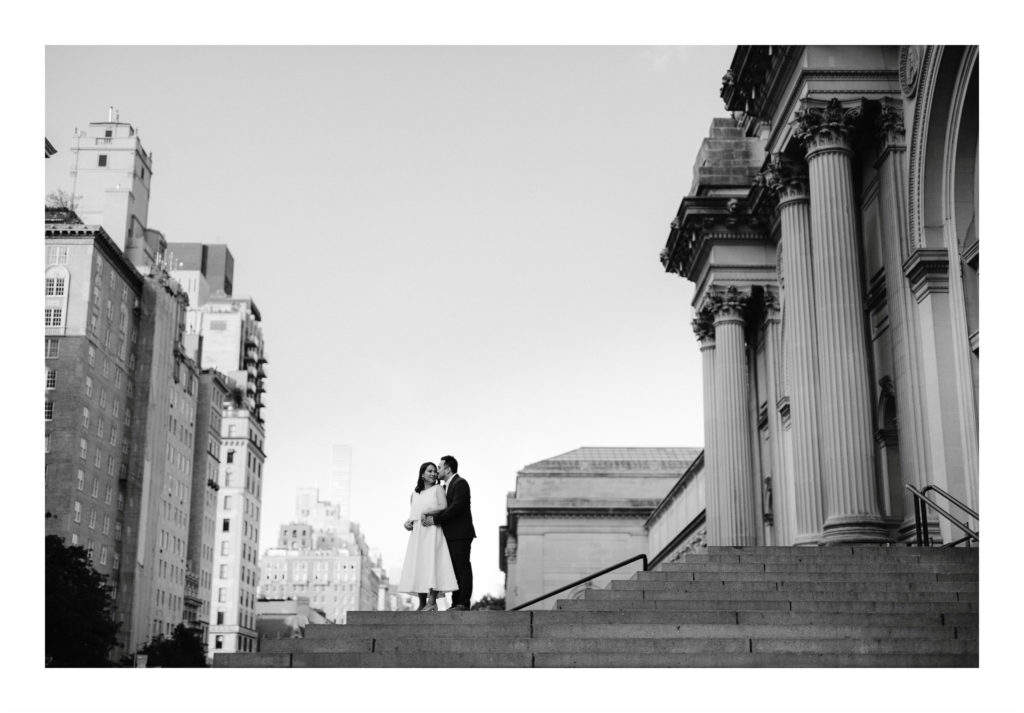 Big sky shot of engaged couple on the steps of The Met in NYC