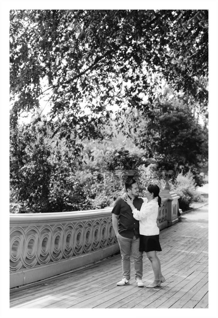 Man and woman laugh with each other on a bridge in central park