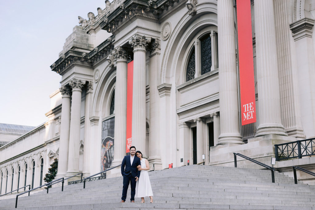Engaged couple pose together on the steps of The Met in NYC