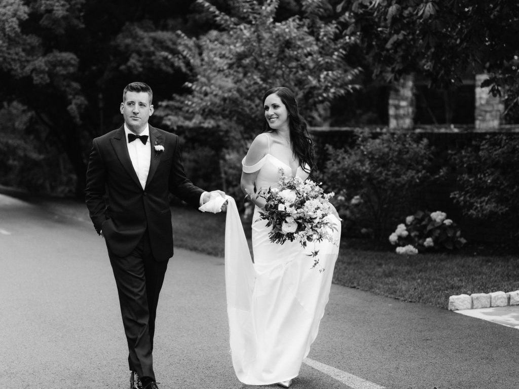 A groom walks the grounds of Le Chateau with his gorgeous bride, smiling and so in love