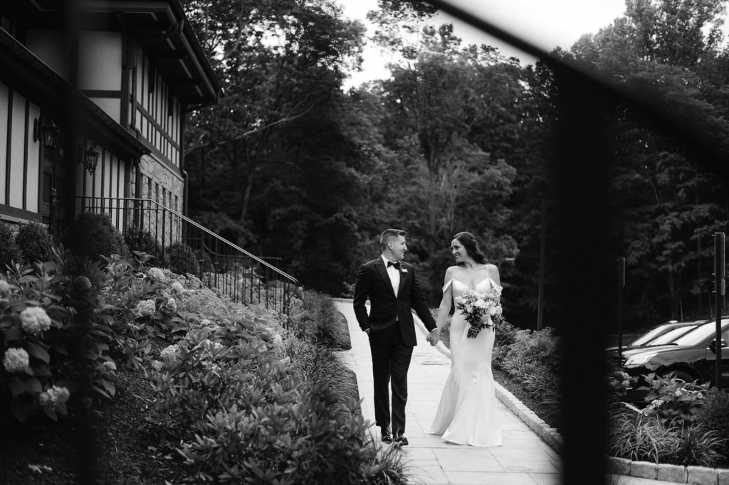 Newlyweds walk along in front of Le Chateau wedding venue in New York. Images by Jenny Fu New York Wedding Photographer