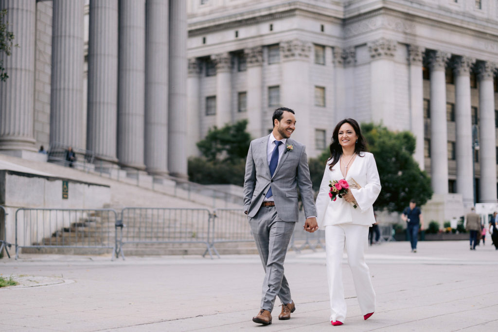 newlywed husband and wife stroll away from City Hall after their chic NYC elopement in New York