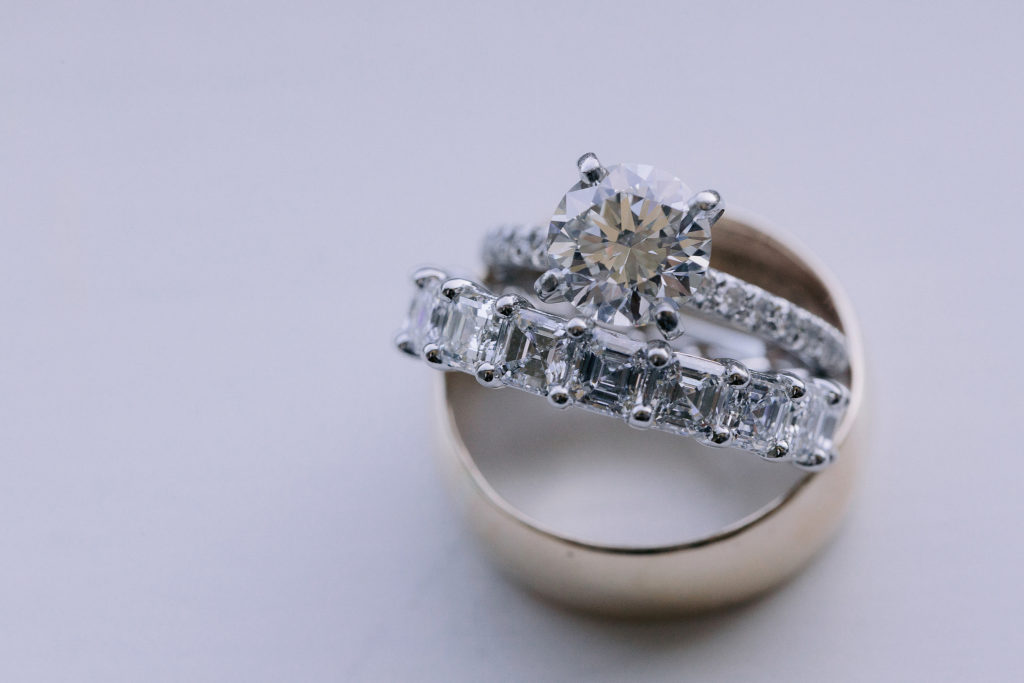 close up of large princess cut diamond engagement ring and multi-diamond wedding band