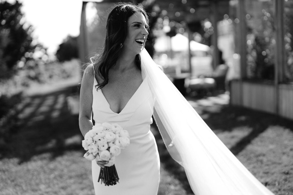 action shot of a bride walking down the aisle and smiling at her cape cod, oceanside tent wedding