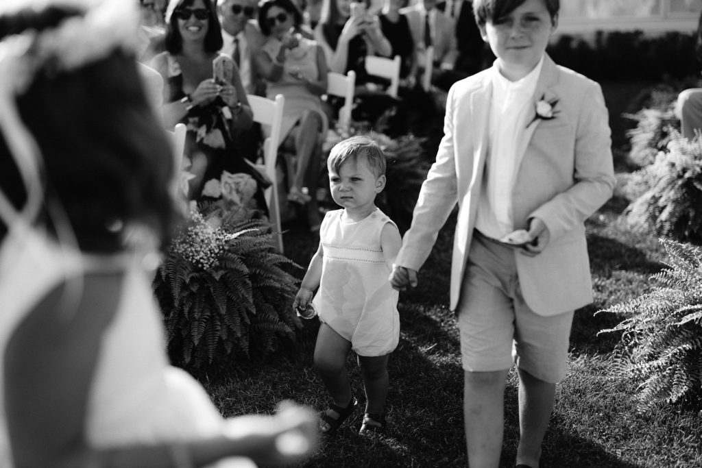 ring bearers, one around 1.5 and the other around 8 years old, walking down the aisle during an outdoor oceanside wedding ceremony in cape cod