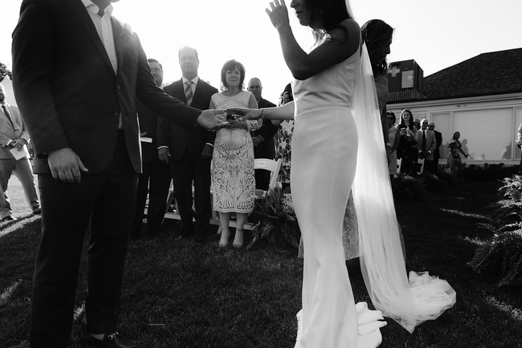 black and white photo of a bride and groom holding hands during their cape cod wedding ceremony