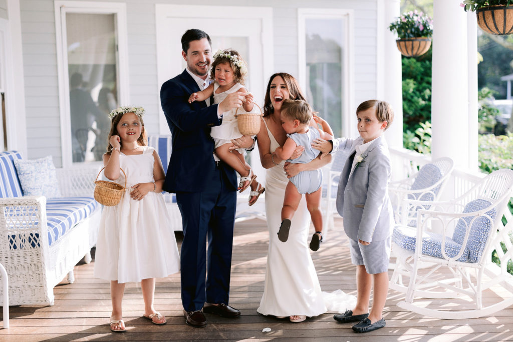 bride and groom pose playfully with their ring bearers and flower girl while flower girl cries hysterically