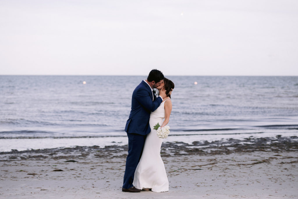 bride and groom kiss oceanside at wianno club in cape cod