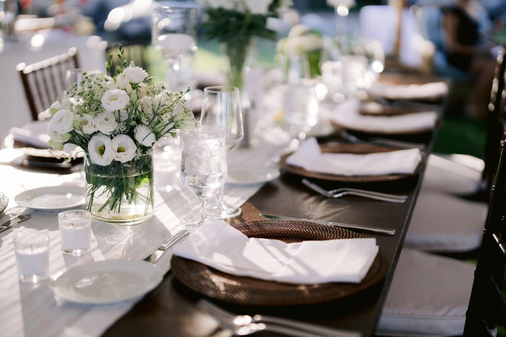 detail shots of the table settings at an oceanside wedding in cape cod with a greenery and white theme.