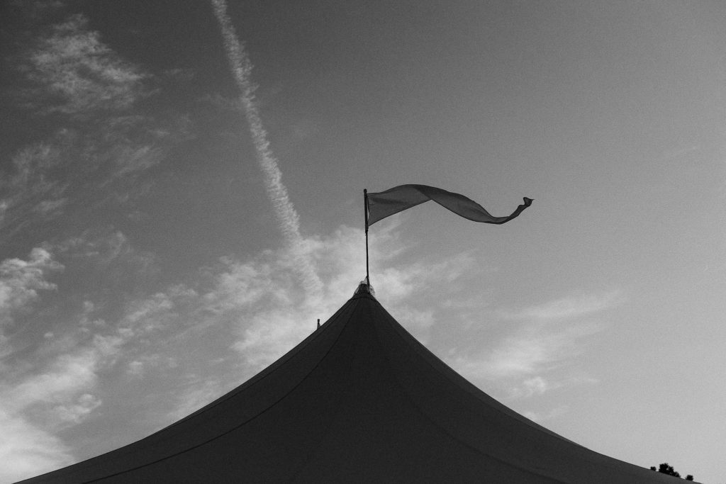 silhouette of tent top and flag set up for an oceanside cape cod wedding