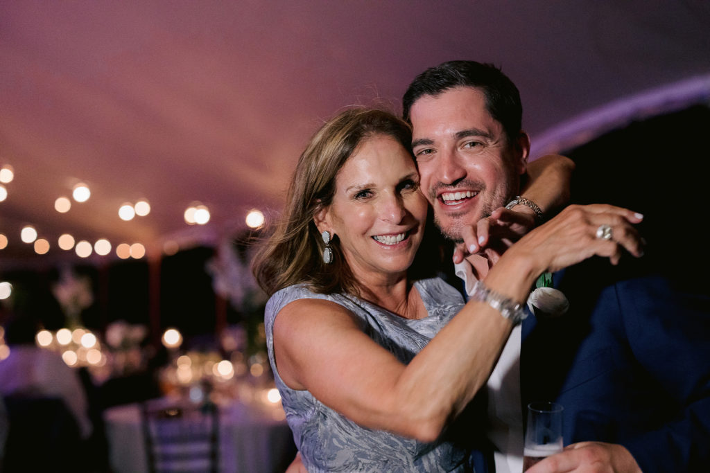 new husband poses for a hug with his mom during the wedding reception on cape cod
