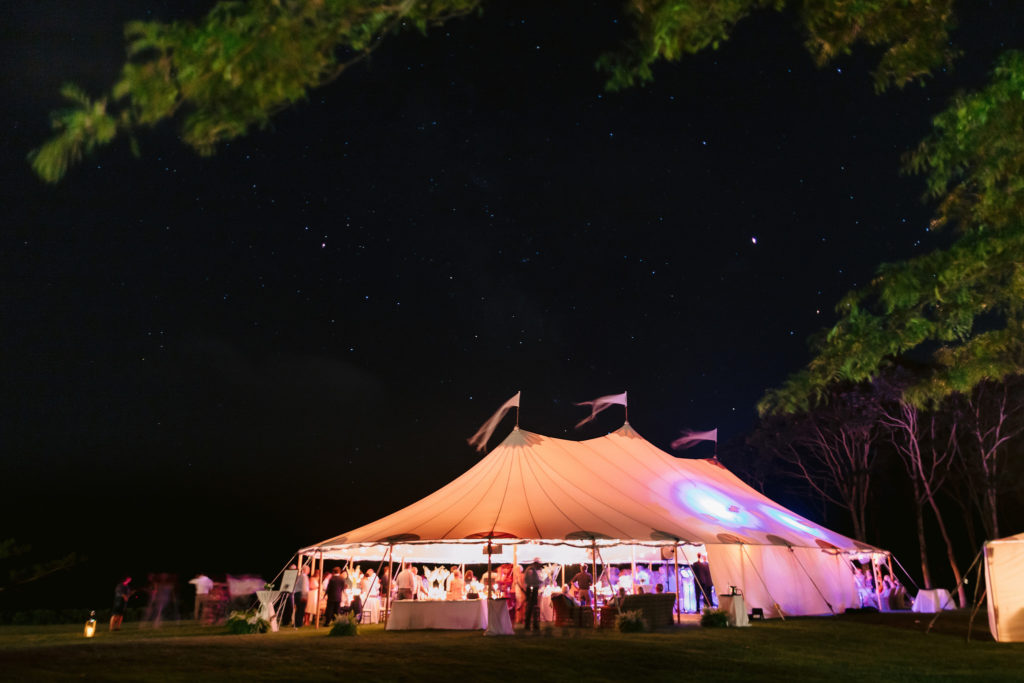 Night shot of a wedding reception tent illuminated against the dark sky