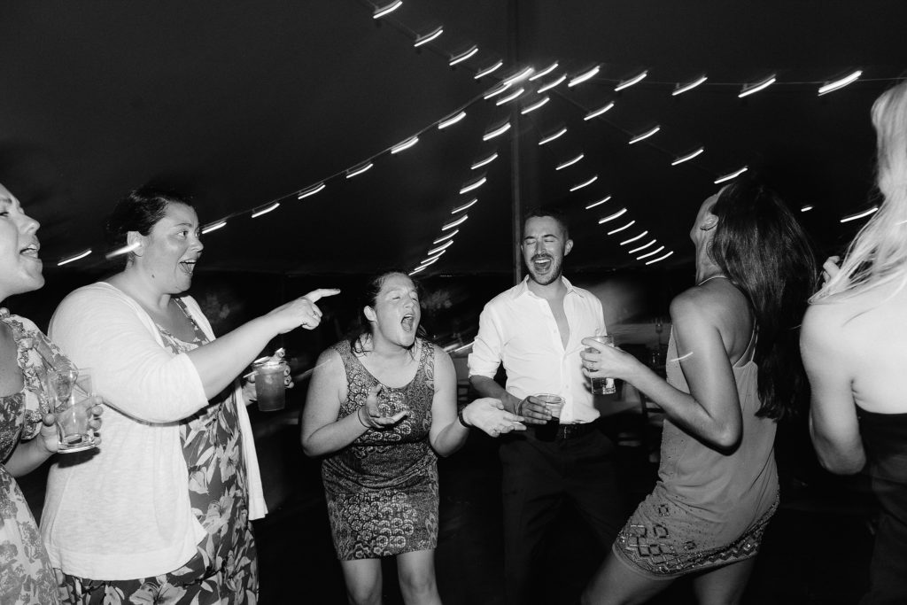 guests dance and enjoy themselves at a tent reception on the shores of cape cod in New York