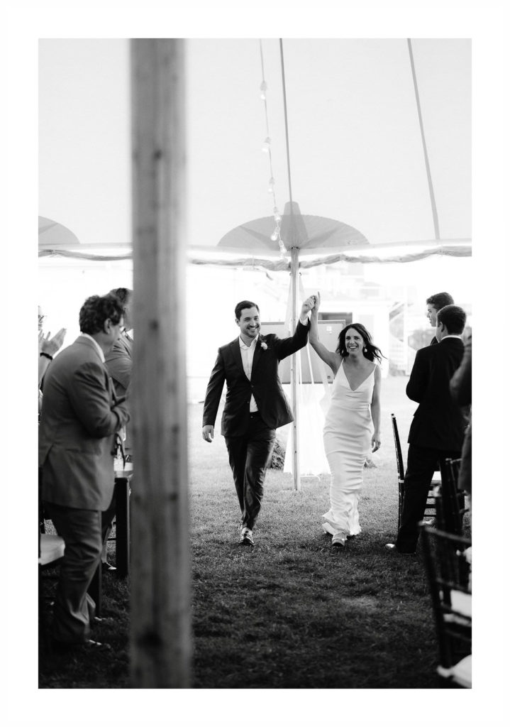 bride and groom enter reception tent at their oceanside cape cod wedding at the wianno club