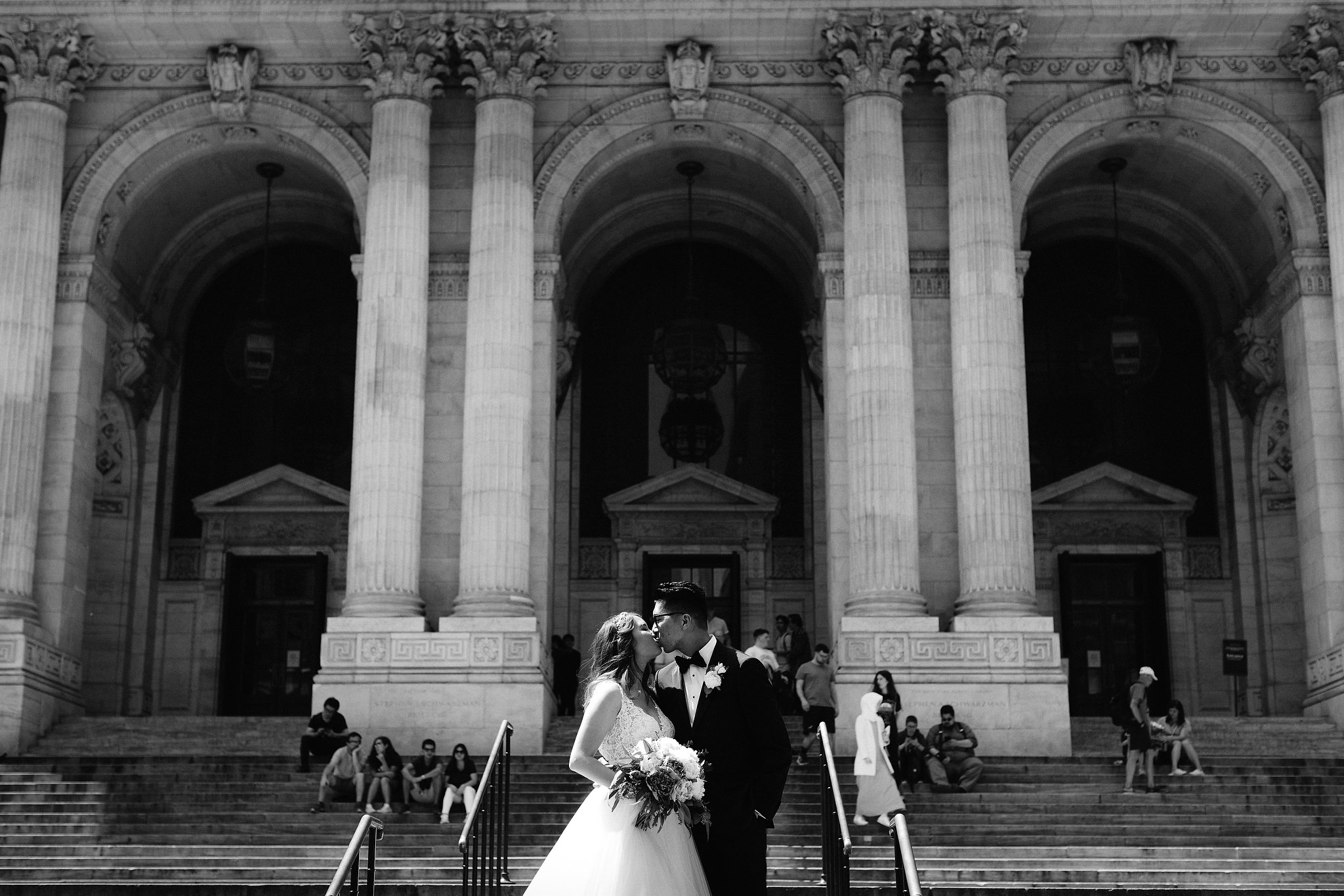 Man and woman kiss outside of the New York Public Library