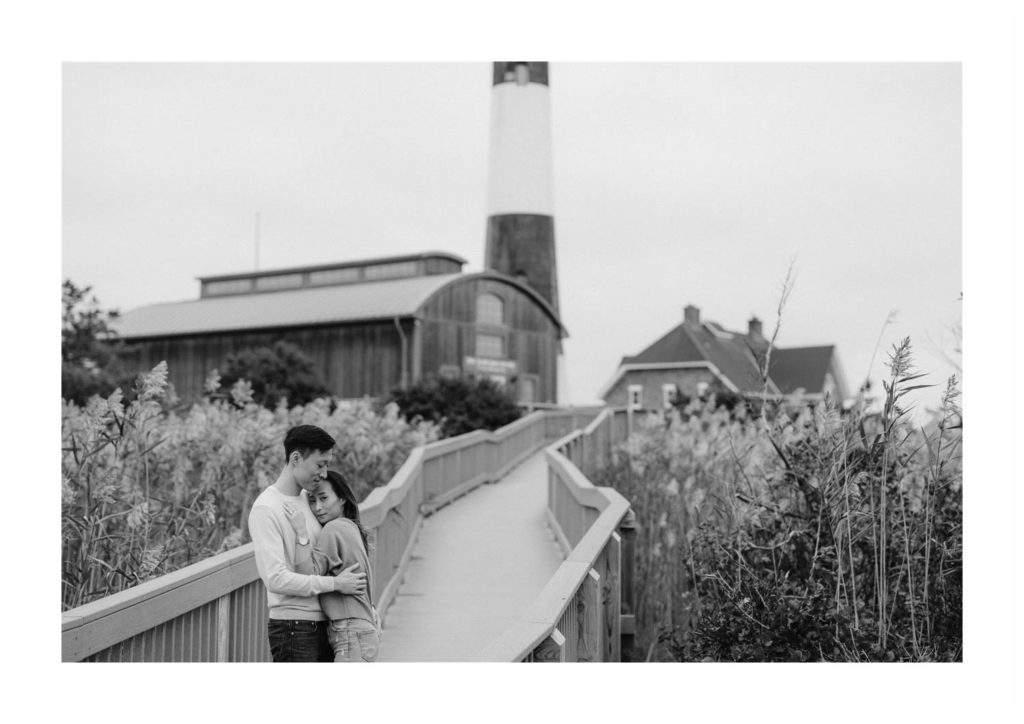 Engaged asian couple, Sally & Albert snuggle each other on the walkway to the Fire Island Lighthouse in Robert Moses State Park
