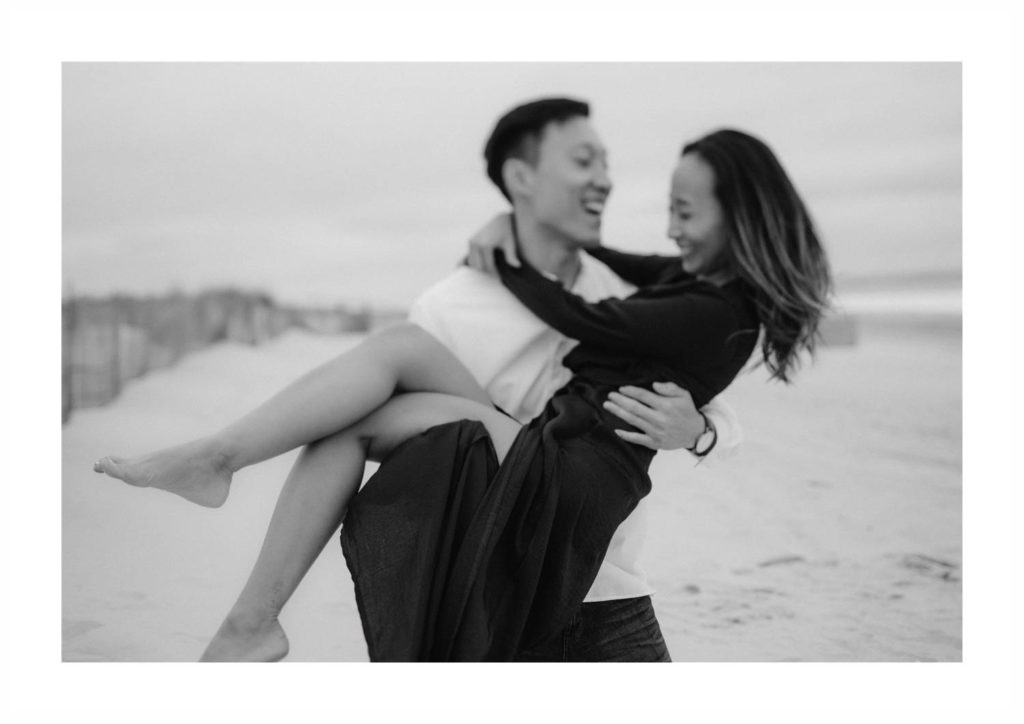 Asian man scoops up his happy fiancee and spins her around while they both laugh. Image by Jenny Fu
