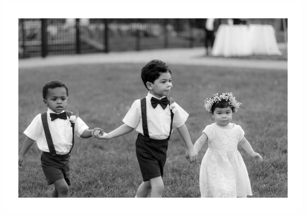 Two little ring bearers and a flower girl walk down the aisle at this New York wedding ceremony set up at Castle Gould in New York
