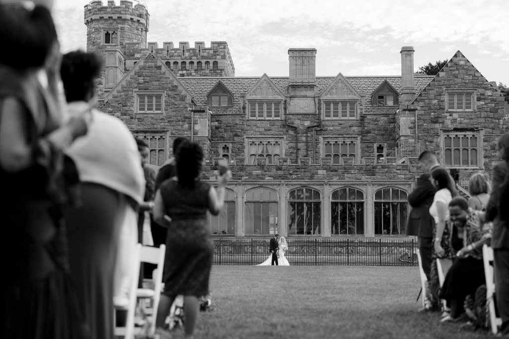 Happy bride walks down the aisle with her father in this outdoor ceremony at Castle Gould in NY