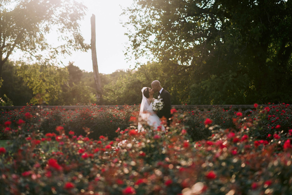Bride and groom stare lovingly at each other at the end of a long bank of wildflowers on the grounds of Castle Gould at the sands point preserve in new york