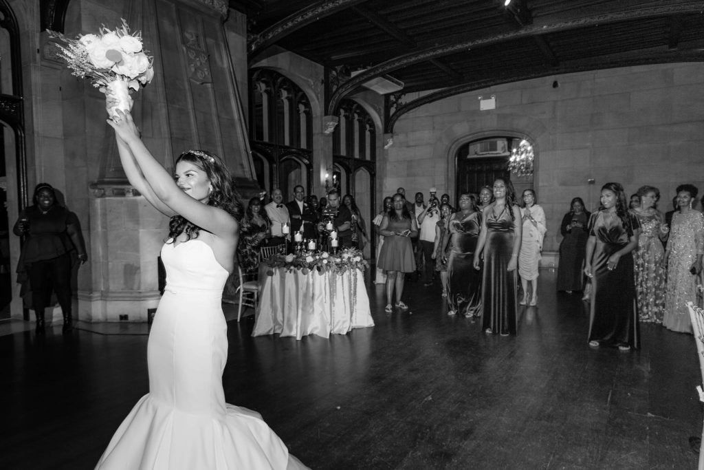 Bride throws her bouquet to a crowd of women behind her at this fun wedding at Castle Gould in new york
