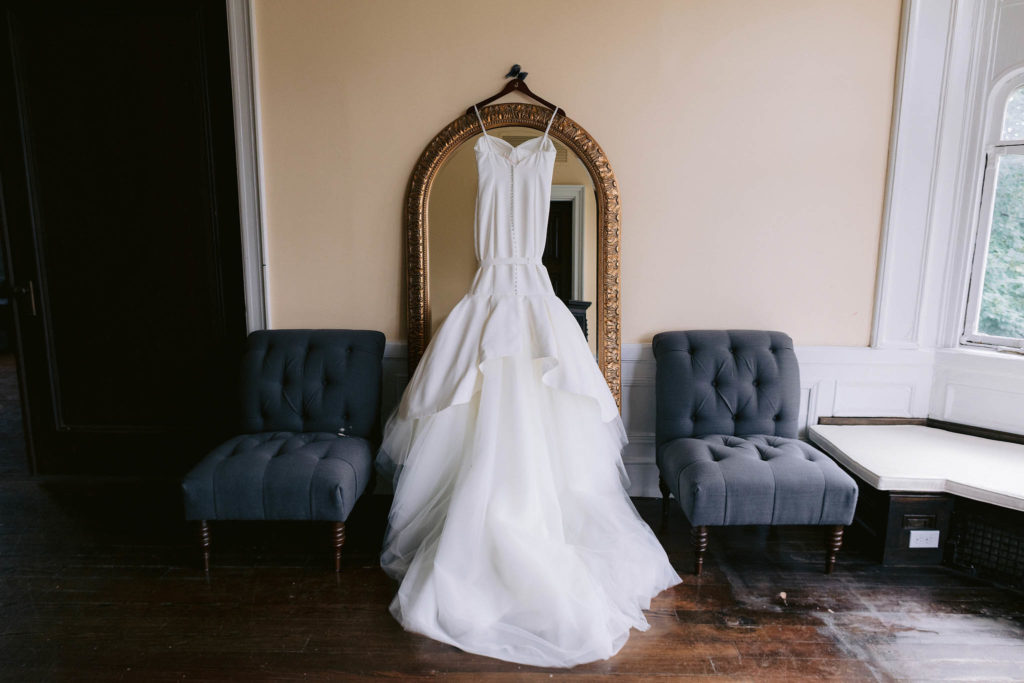 Wedding gown hanging from an ornate, antique mirror at Castle Gould in New York