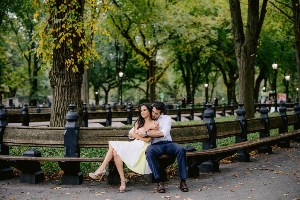 Newly engaged young couple snuggles up on a park bench in New York City's Central Park. engagement photos by Jenny fu Wedding photographer