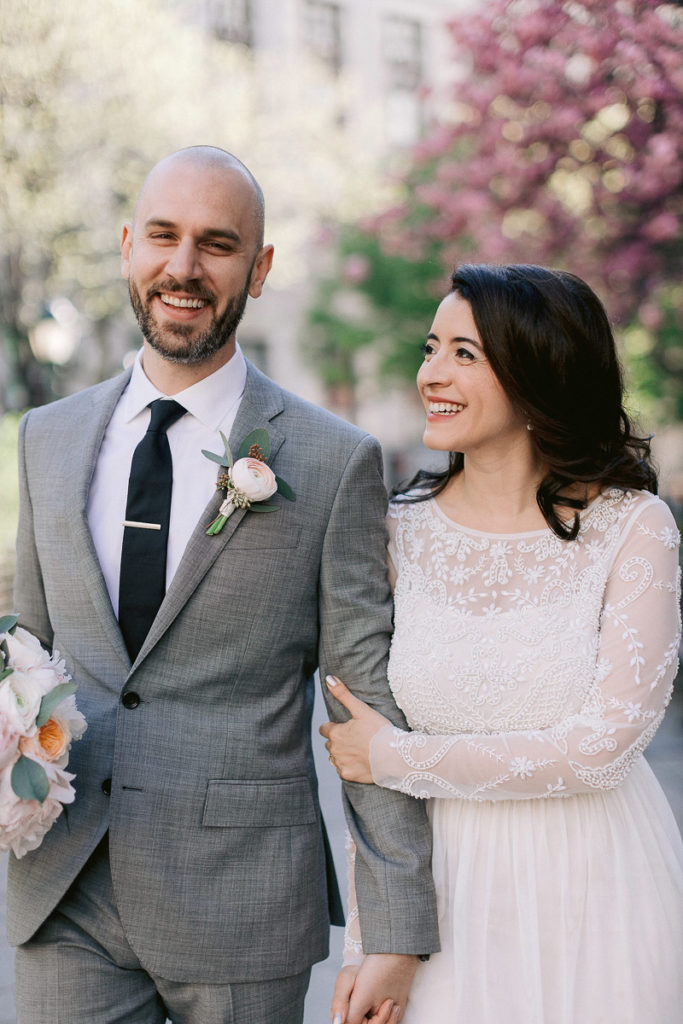 Newlyweds stroll around the garden at New York City Hall smiling and giggling after eloping minutes before