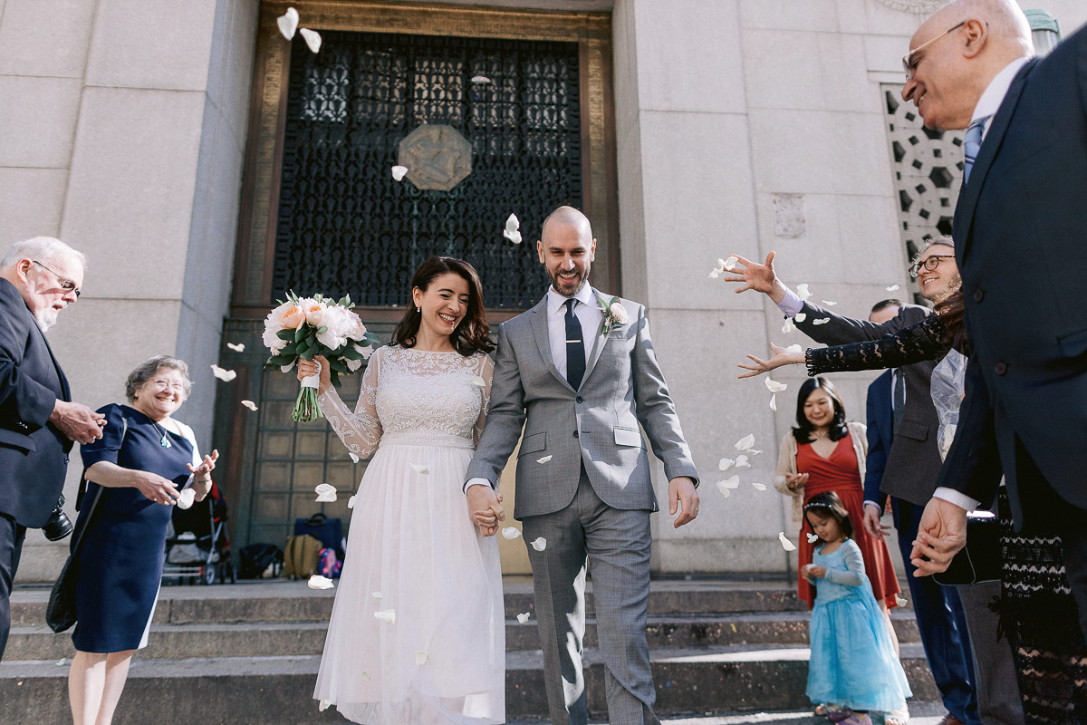 A newly married couple are all smiles as they walk down the steps of New York City Hall