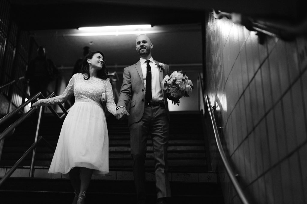 A man and woman walk down the subway steps on their way to New York City Hall on their way to elope with jenny fu photography