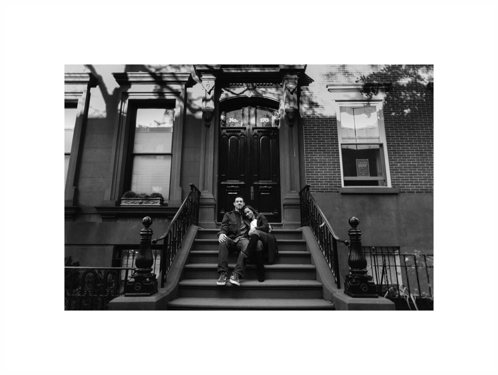 Man and woman sit on the steps of a Brownstone in Brooklyn Heights in NYC. Images by Jenny Fu Studio