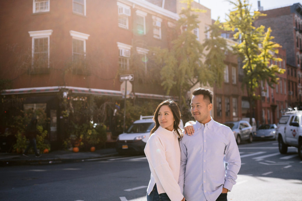 a happily engaged asian couple pull a chic pose as the sun sets in the west village of new york