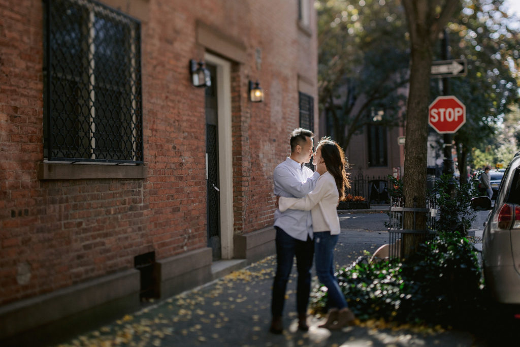 a newly engaged asian couple steals a moment in a back alley of a brownstone in the west village of new york city