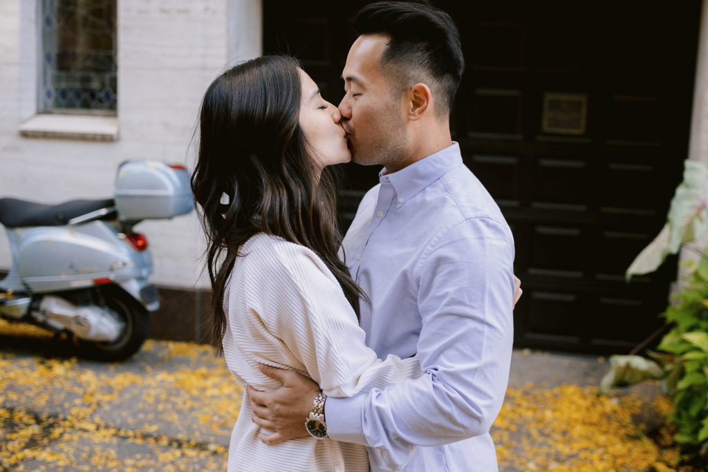 an engaged asian couple give each other a quick smooch in the west village of new york city on a beautiful fall day