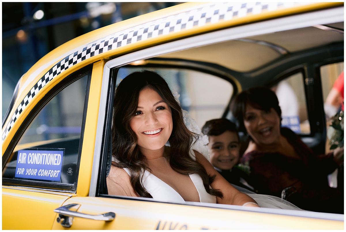 Gorgeous bride looks out the back window of a yellow cab in new york with her mom and son behind her in the cab with her. Editorial image by Jenny Fu.