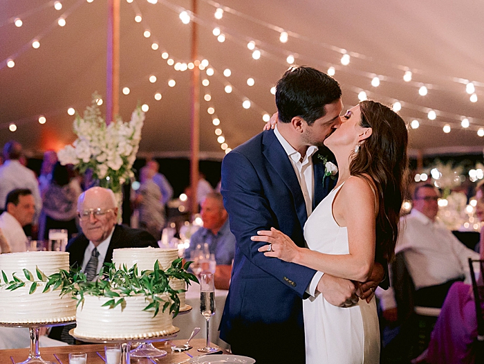 bride and groom share a kiss during their cake cutting at their wedding reception