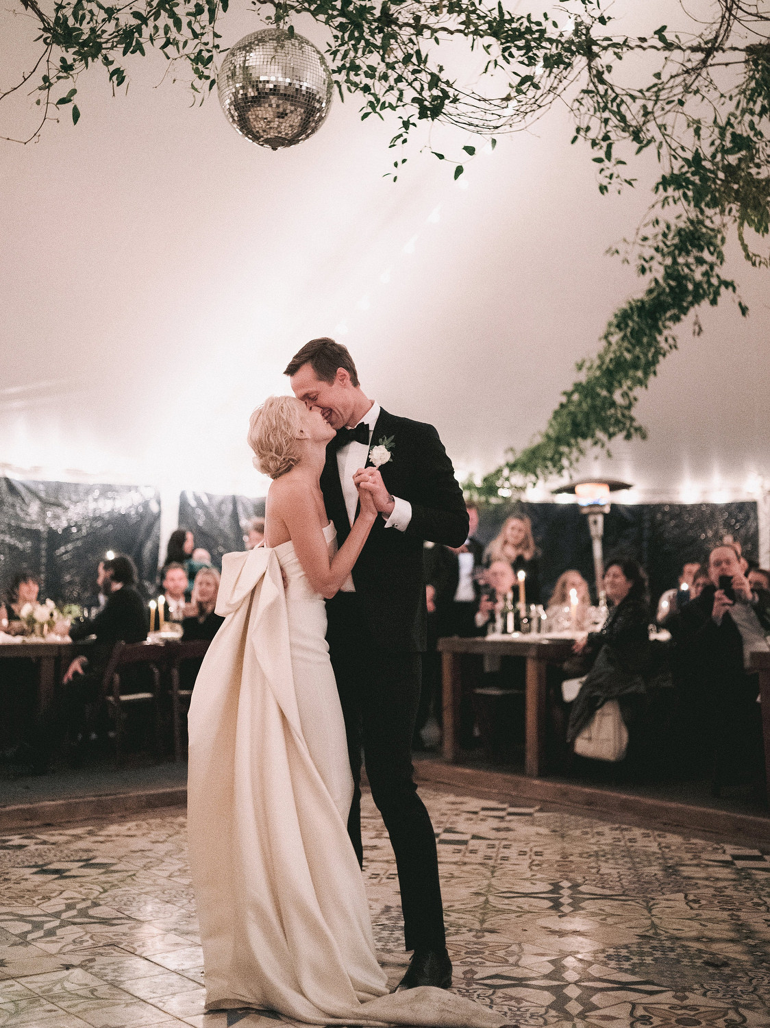 Bride and groom share their first dance under a beautiful hanging vine and a big disco ball.