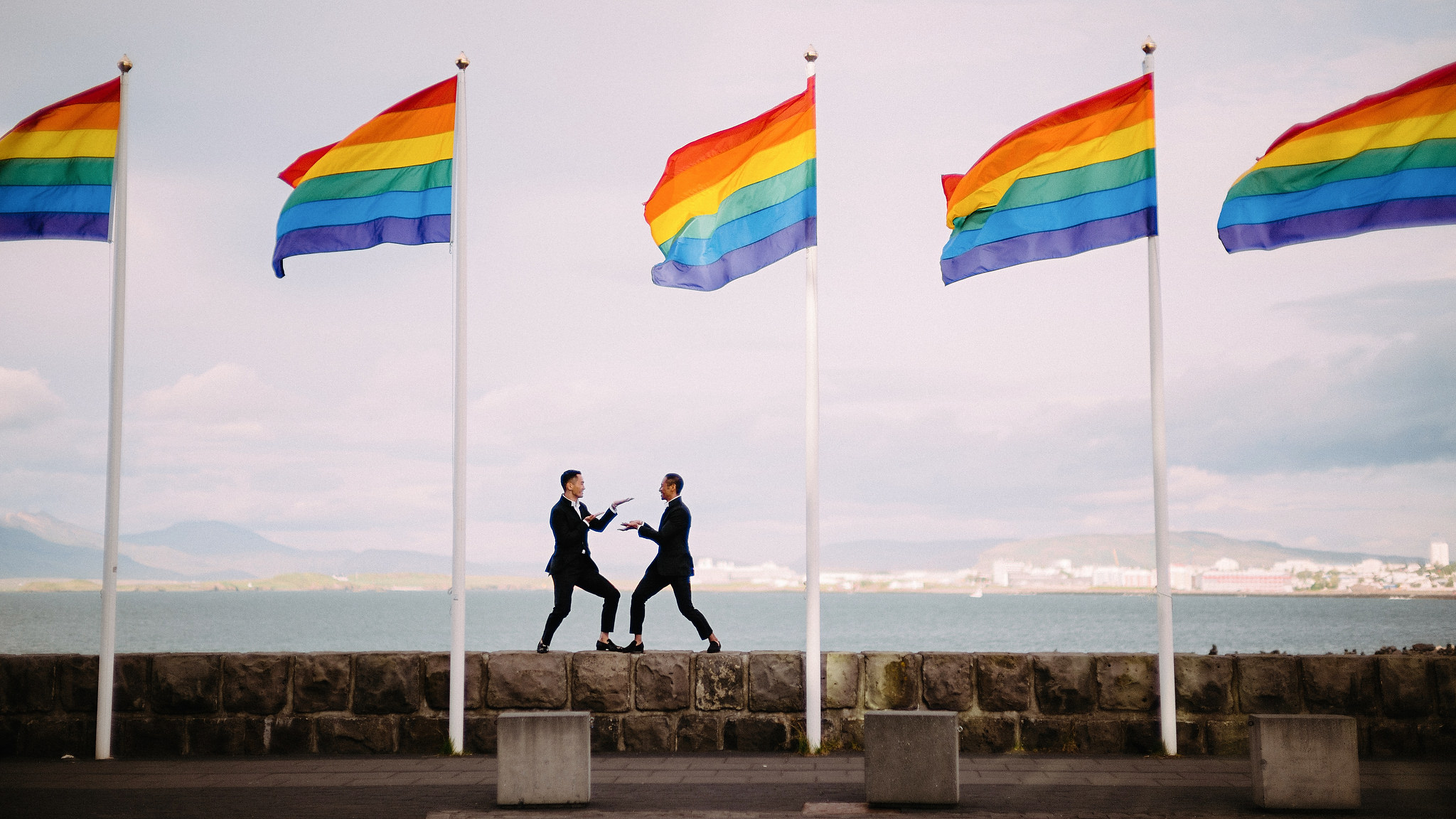 Same sex couple kissing with rainbow flags