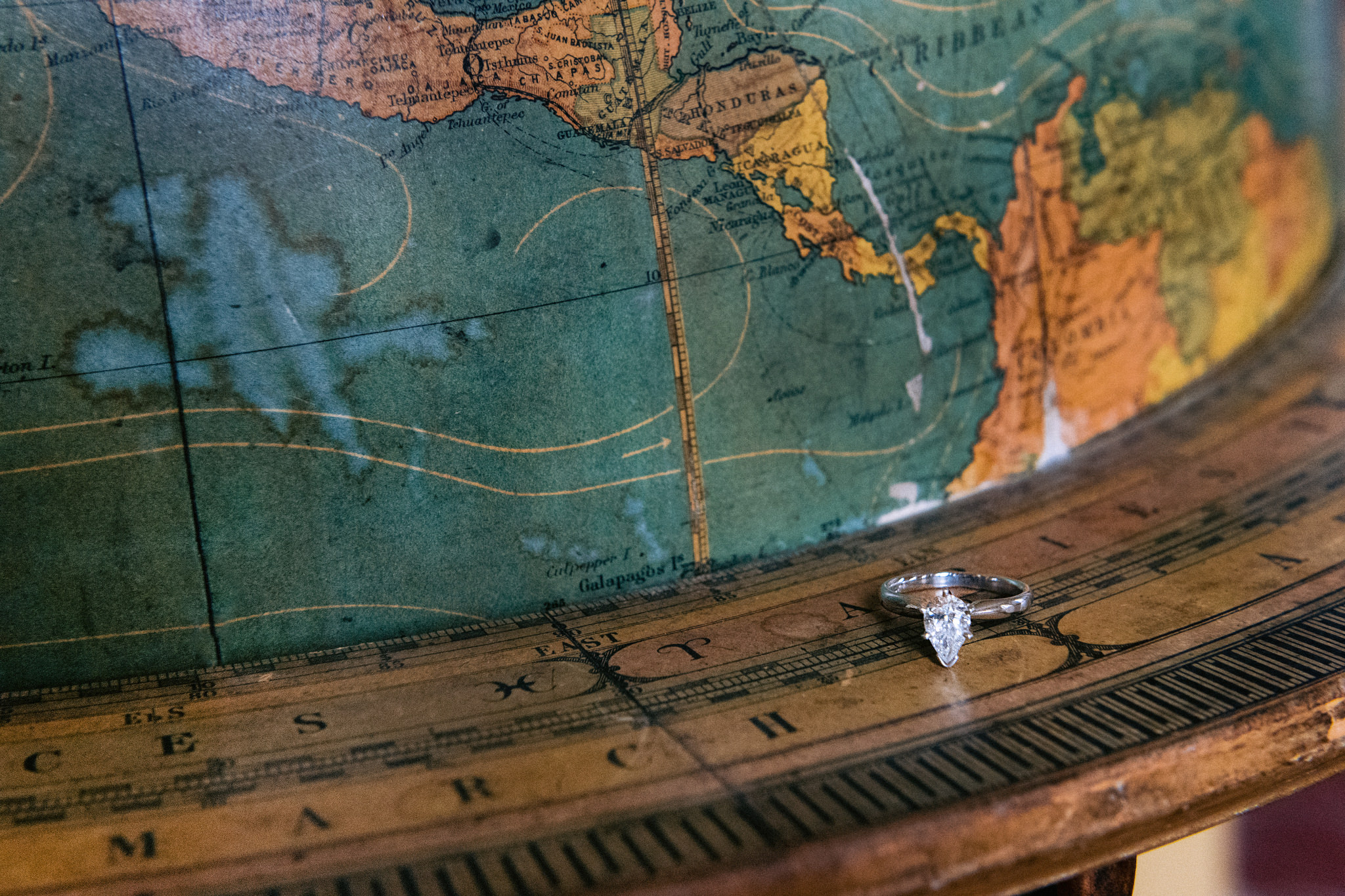 Close up photograph of a globe with engagement ring on it taken by Jenny Fu Wedding Photographer