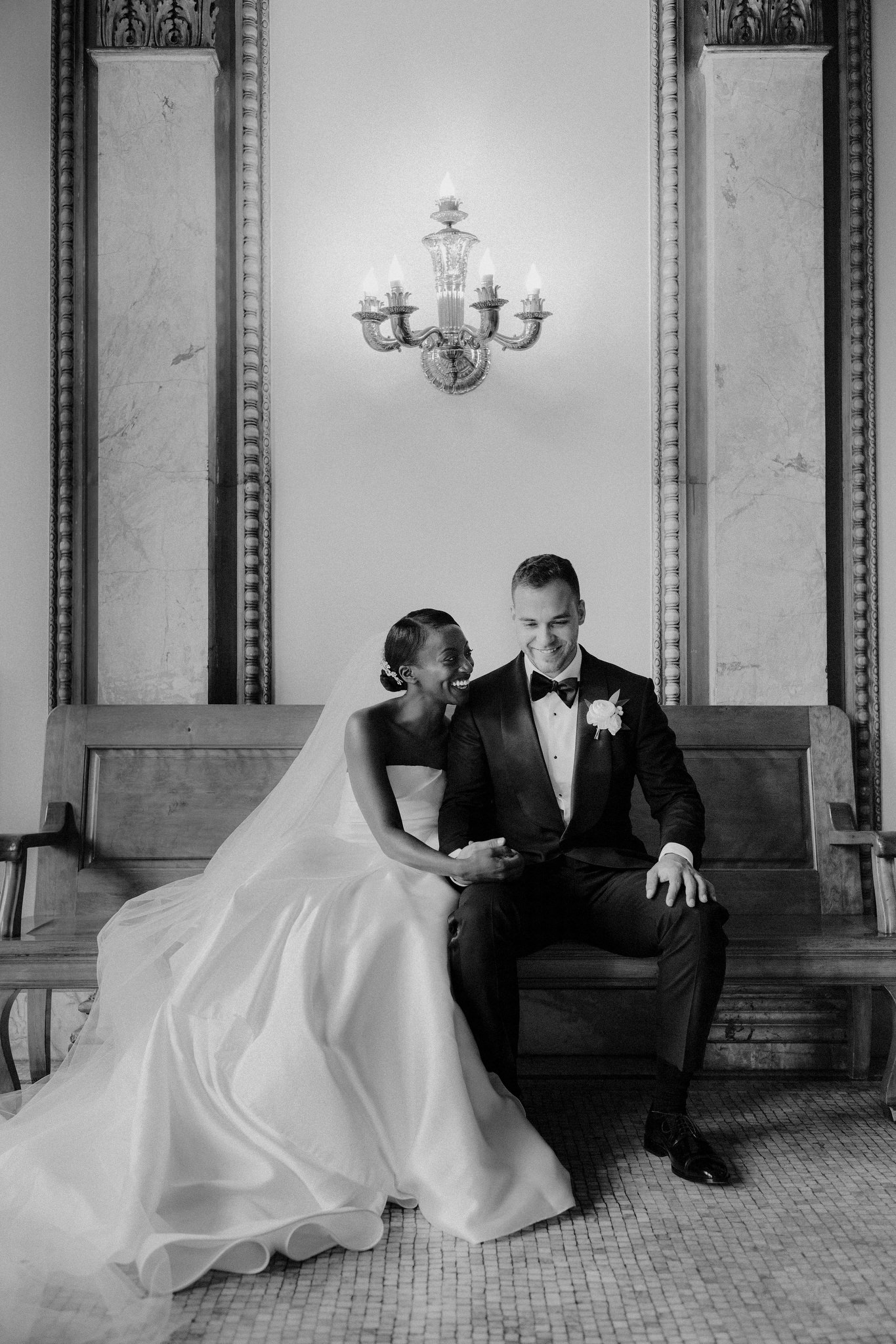 Couple sitting together on a bench in wedding dress and suit
