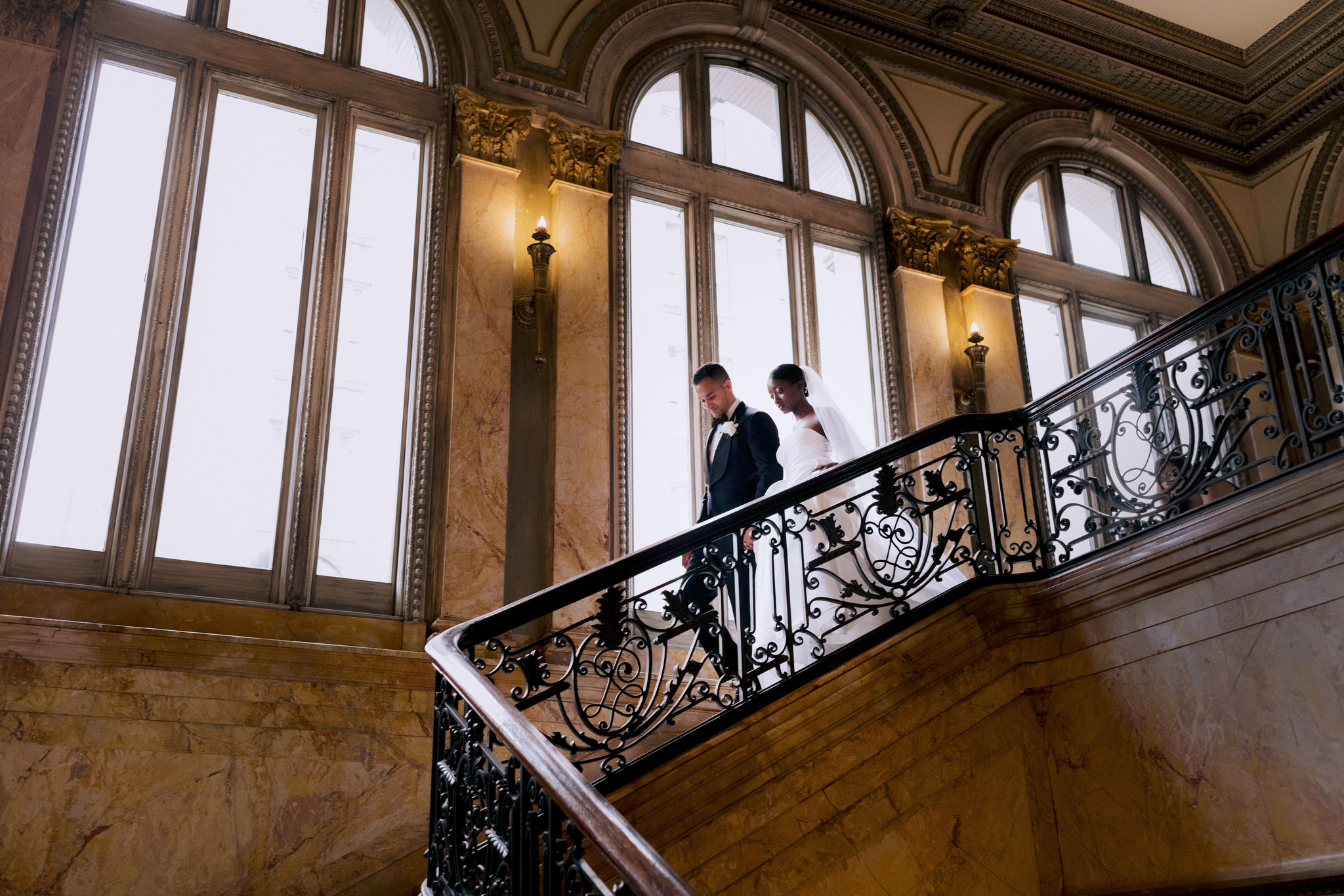 Interracial couple walks down staircase together on wedding day at Providence Public Library