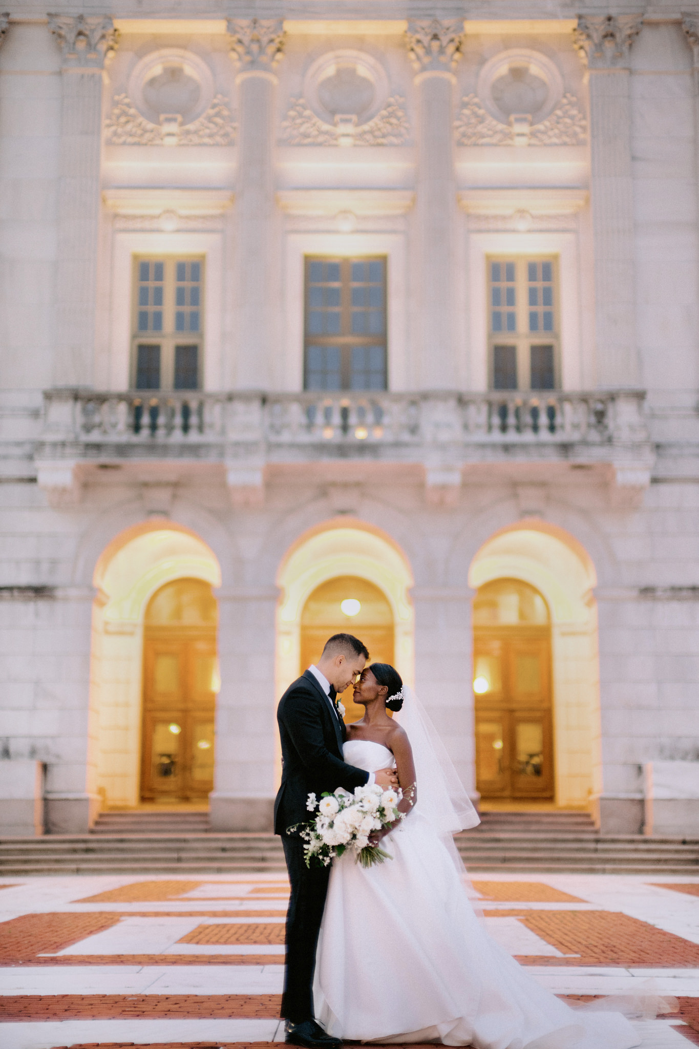 Bride and groom with their foreheads touching intimately as they stand outside the the Providence Public Library