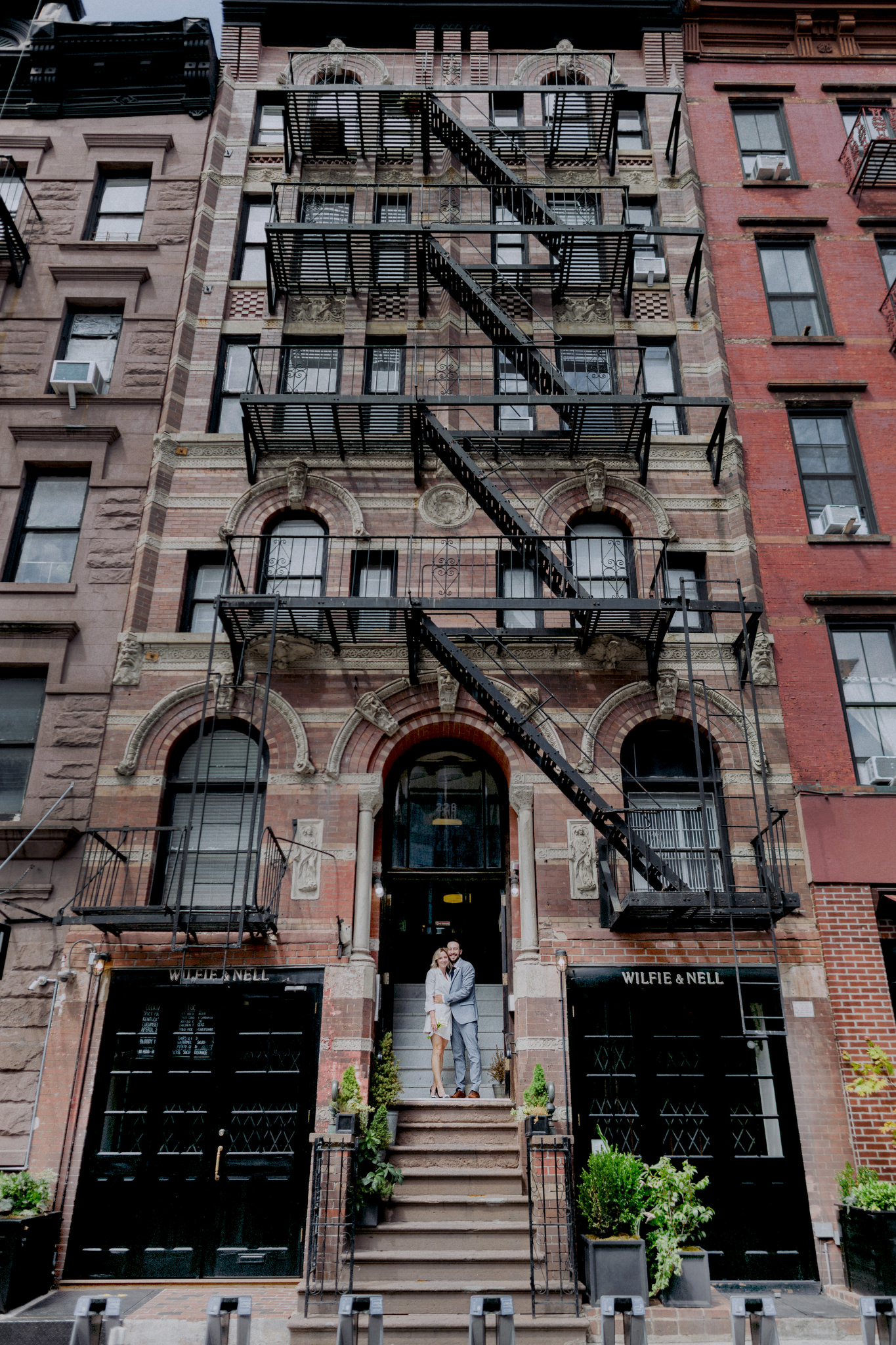 Bride and groom standing on steps of old building in Manhattan on wedding day