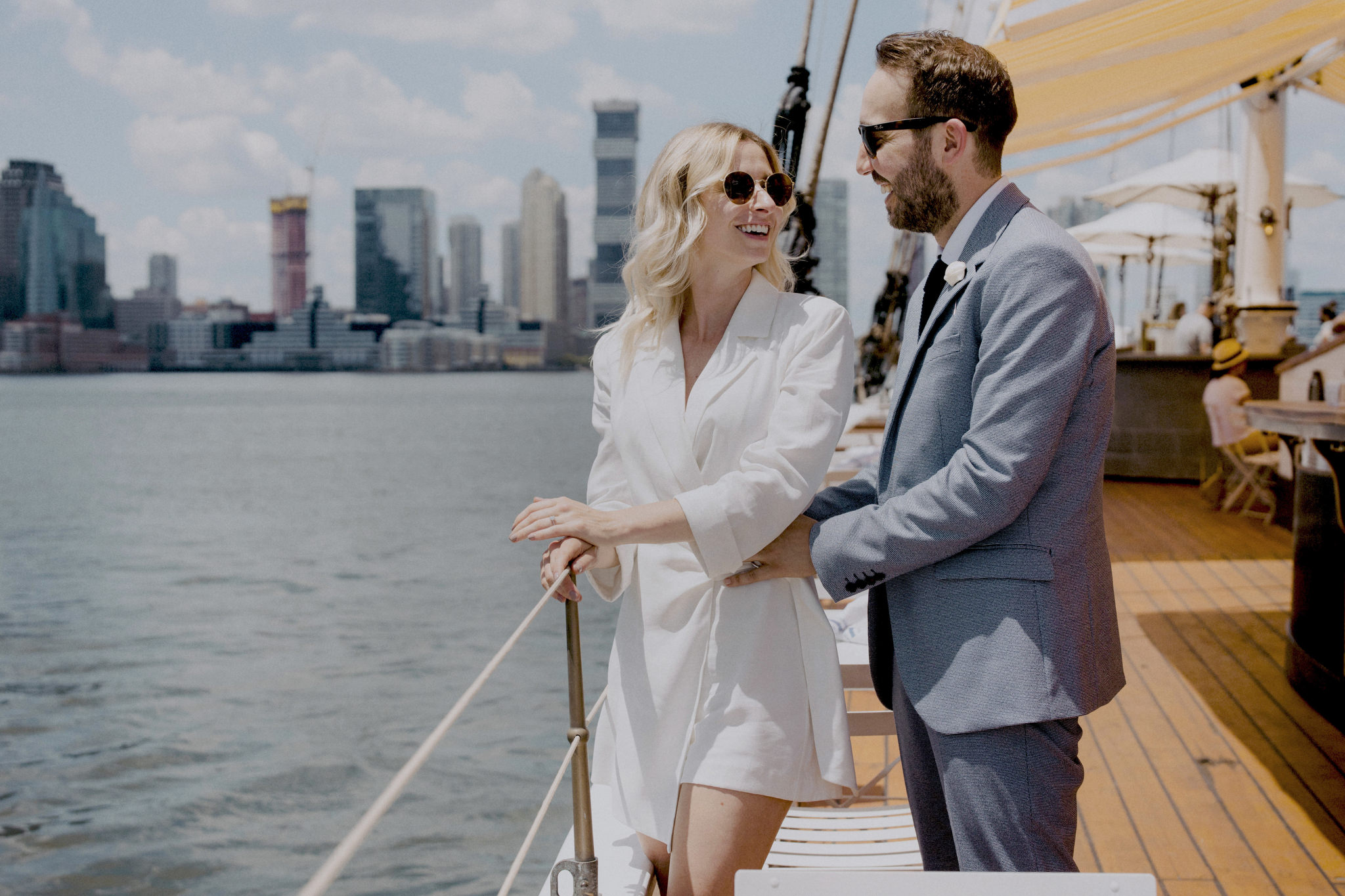 Newly married couple wearing sunglasses looking at each other smiling on Grand Banks boat in Manhattan