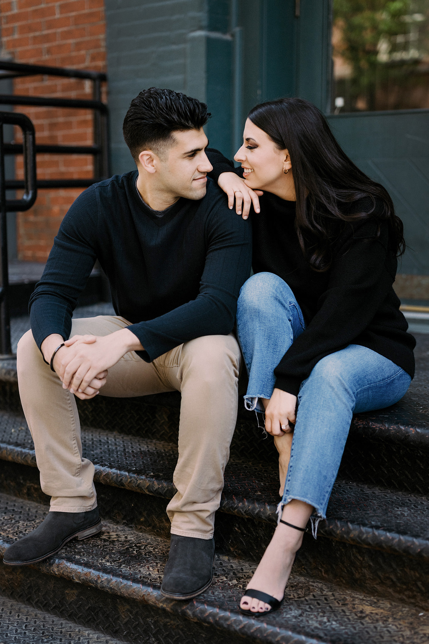 Engaged couple looking into each others eyes sitting on steps