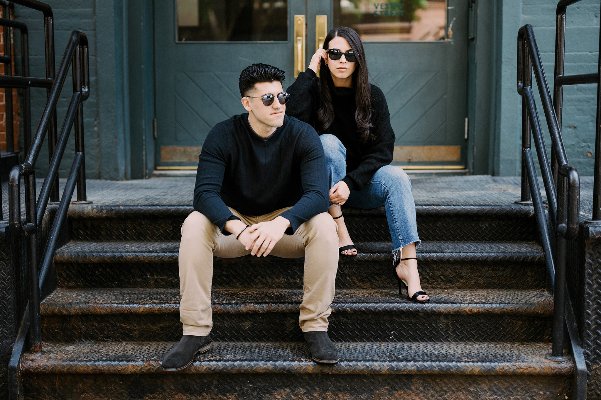 Couple sitting on steps wearing sunglasses for urban engagement photos