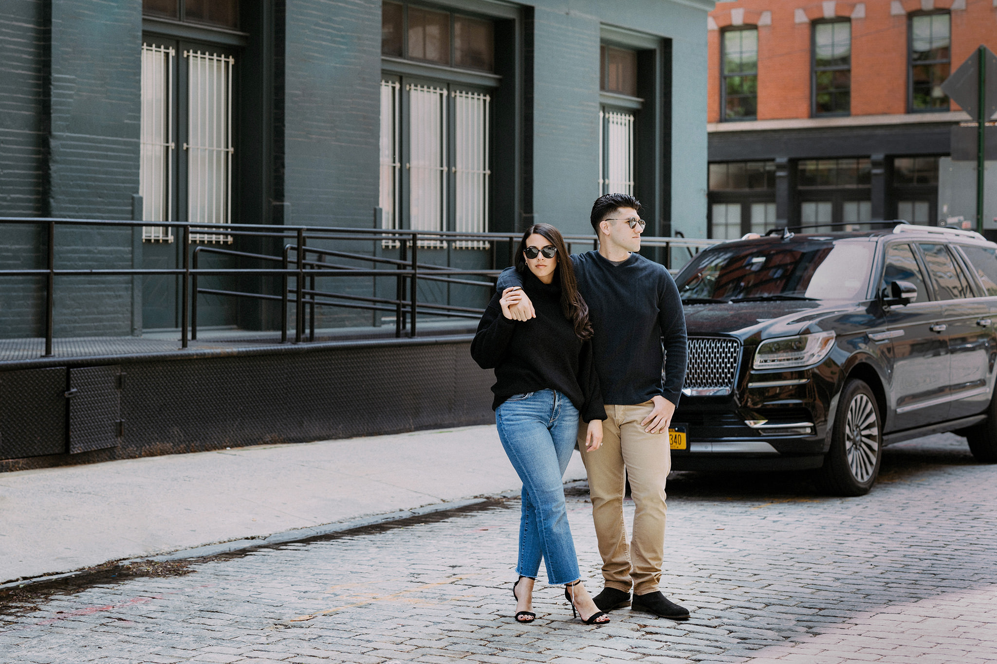 Engaged couple standing together in Manhattan street in front of black SUV
