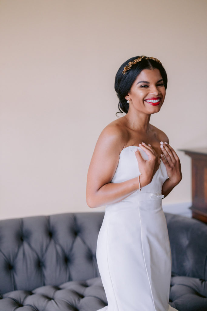 Bride smiling after putting on wedding dress