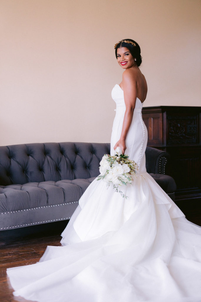 Bride holding bouquet at side showing off train of wedding dress